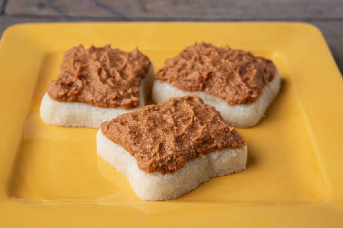 Dysphagia-friendly BBQ pork on pureed bread on a yellow plate