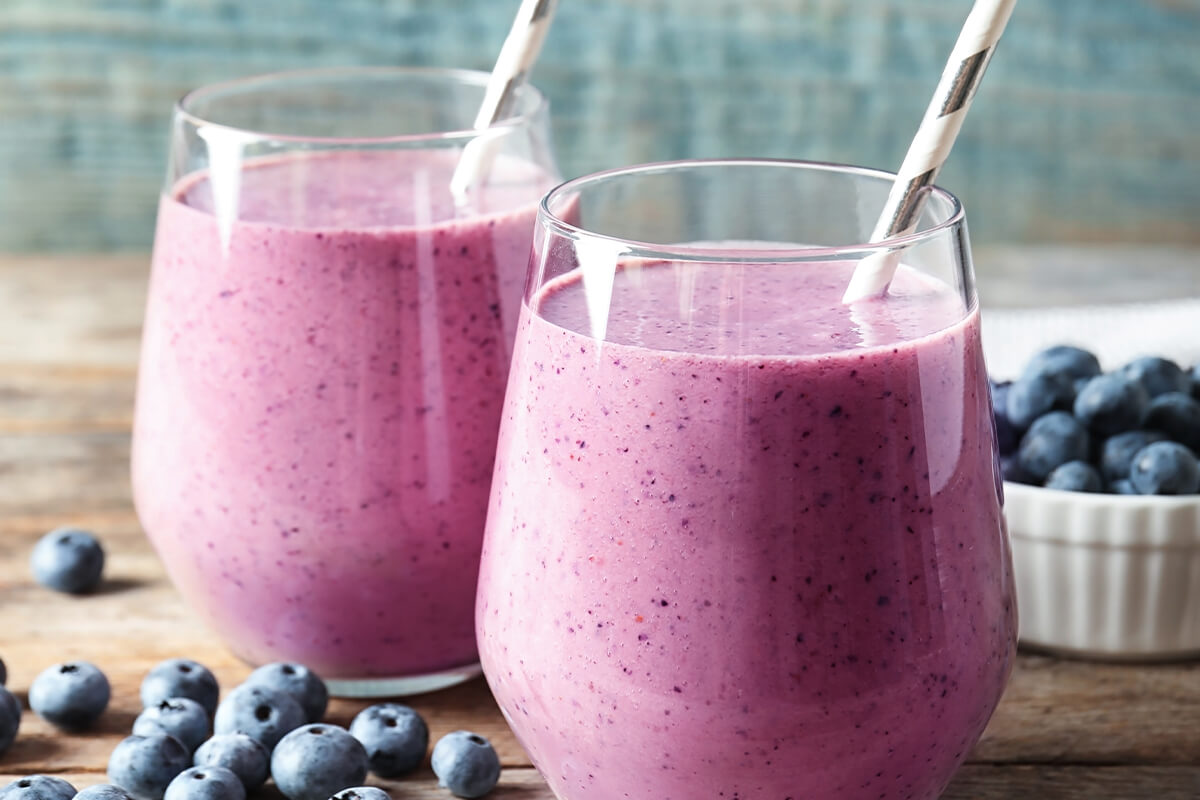Blueberry Smoothies on a table surrounded by blueberries