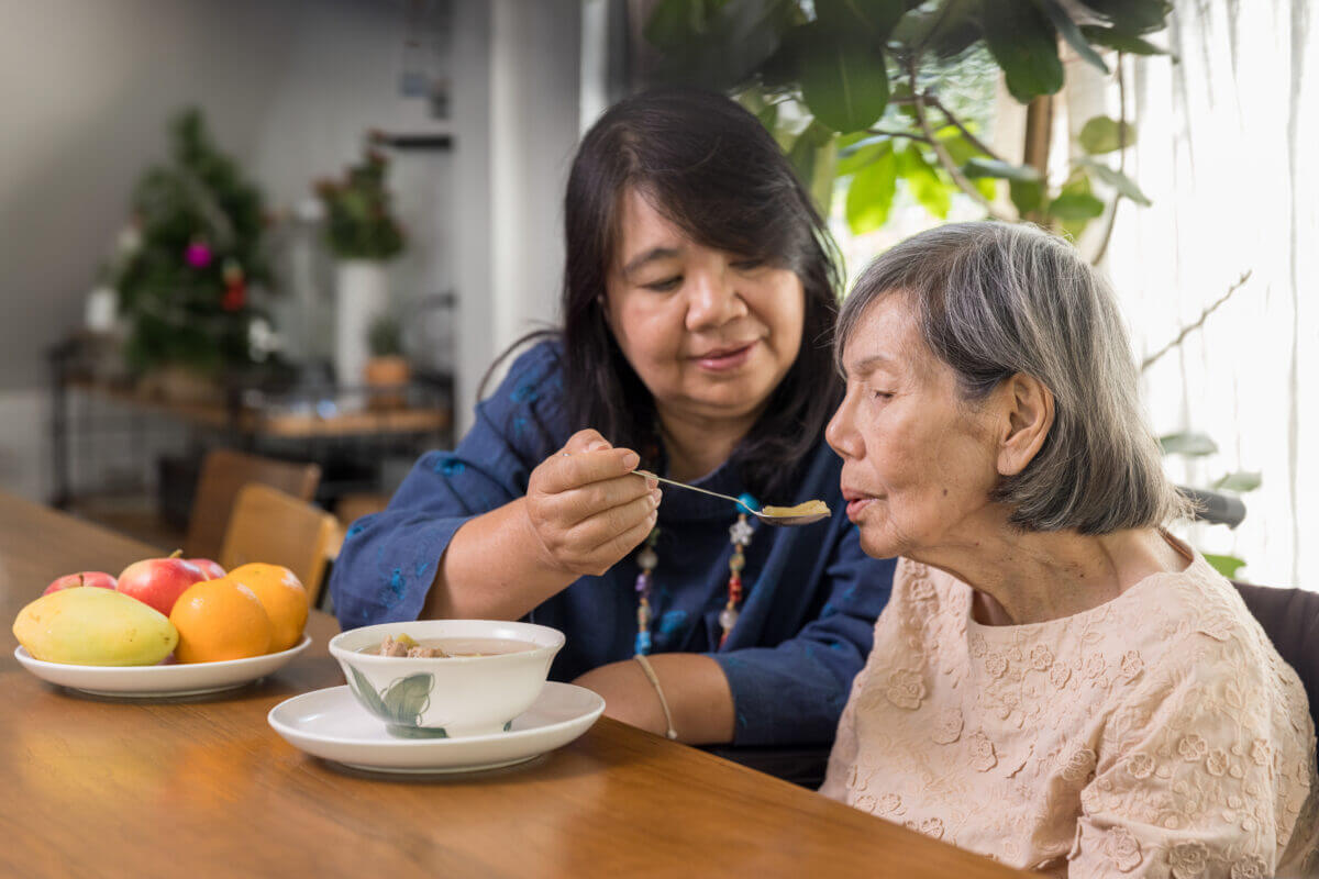 Daughter feeding elderly mother